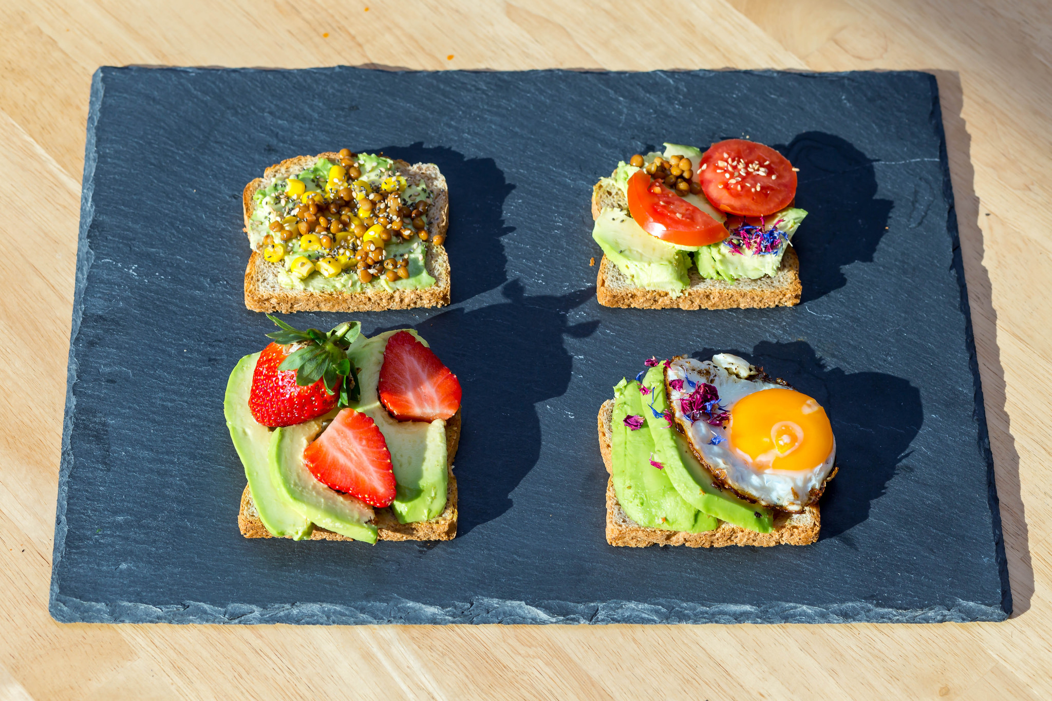  Avocado toast with lentils, strawberries, fried egg and tomato.